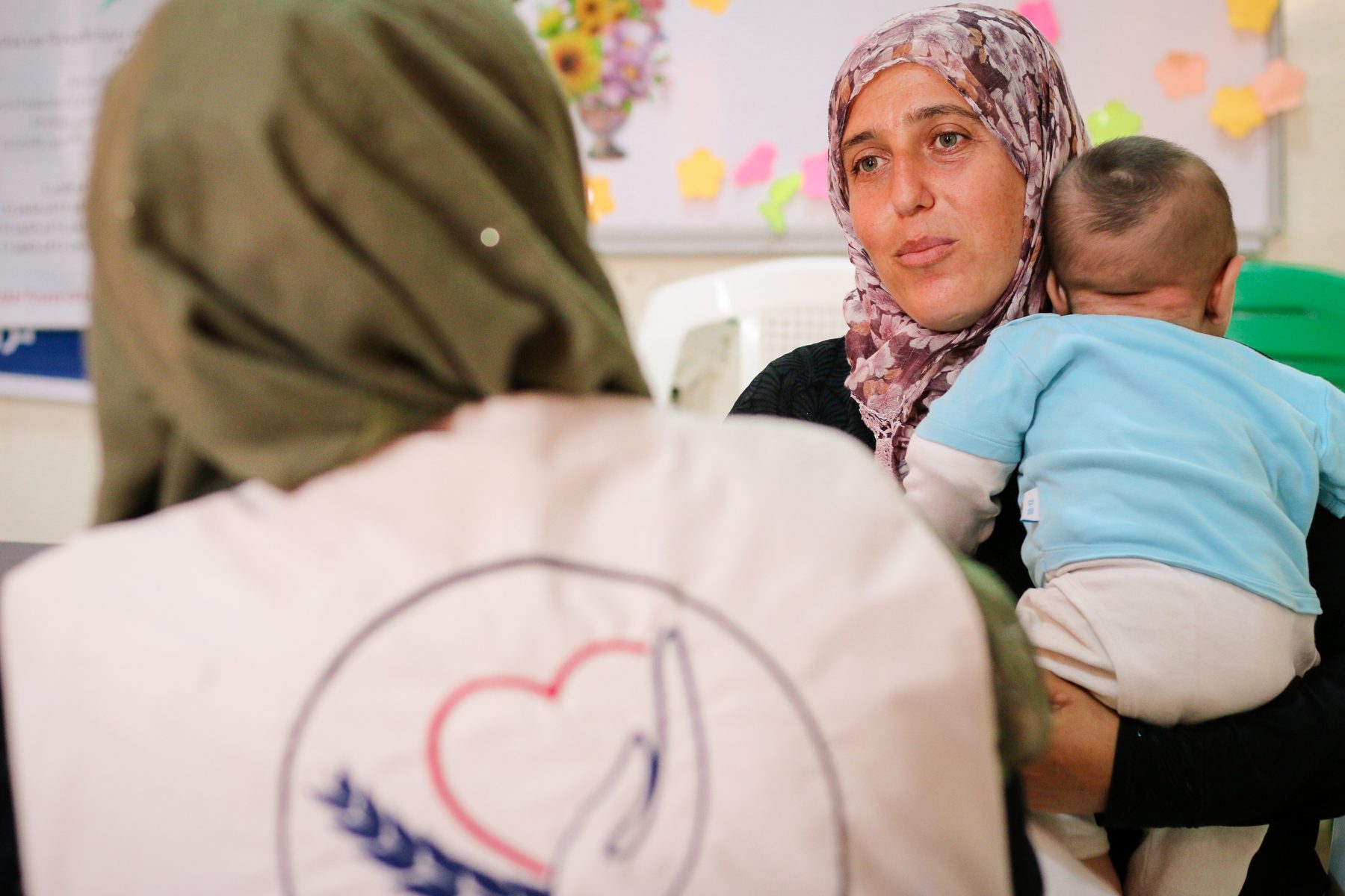A woman holds her baby during a consultation with an SRD worker